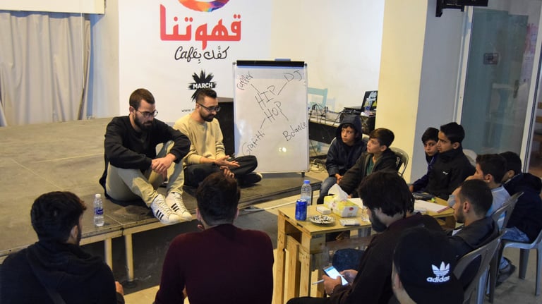 a group of people sitting around a table attending a workshop on rap music composition