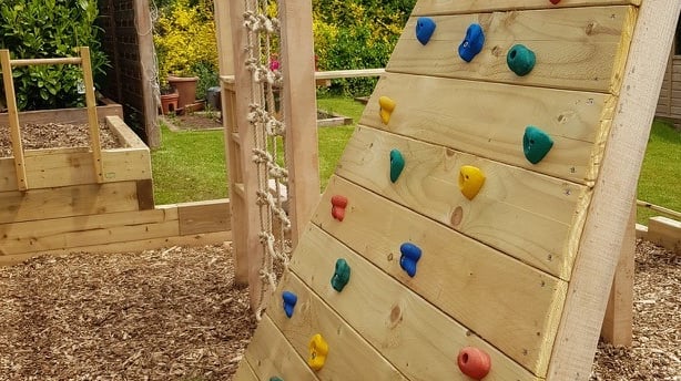 Oak and Larch play structure in a garden with climbing net, climbing wall and monkey bars