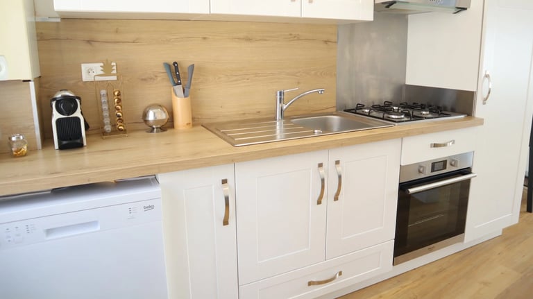 Cuisine équipée moderne avec four, plaques, lave-vaisselle et plan de travail en bois