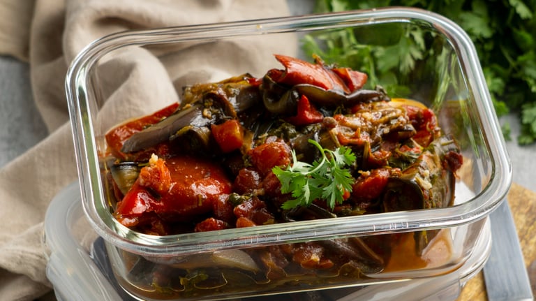 a glass container with vegetables and vegetables on a cutting board