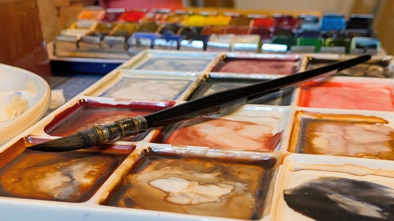 Waterverf palet met penseel en aquarel napjes, gemengde kleuren op een bord