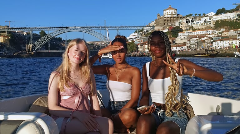 Three girls posing for a photo on the Endure speedboat with Dom Luís I Bridge in the background