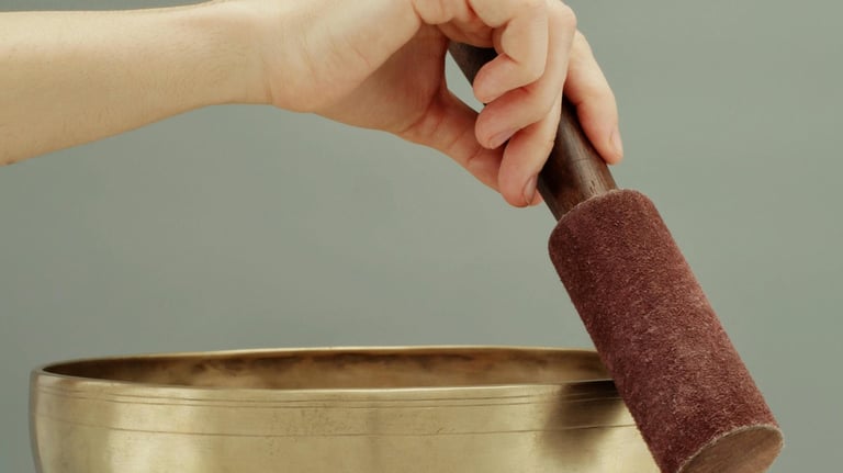 a person holding a singing bowl with a hand holding a small object