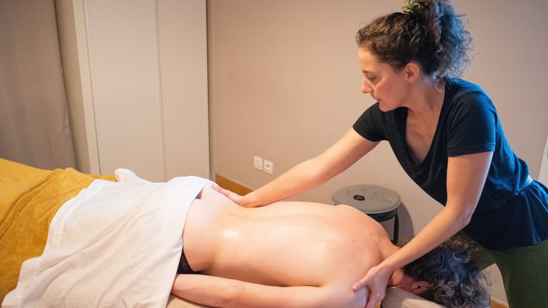 Masseuse qui masse le bas du dos et l'épaule d'un client allongé sur le ventre avec placard en fond