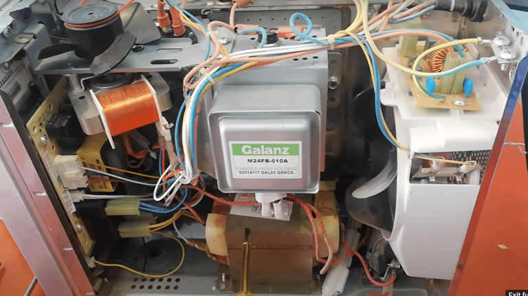 a picture showing internal component of a microwave. Magnetron and transformer is shown