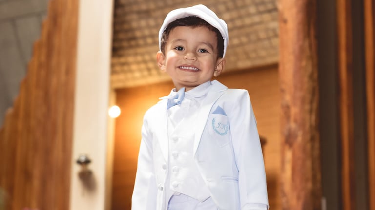 Foto profesional de bautizo de un niño joven en traje blanco de marinero