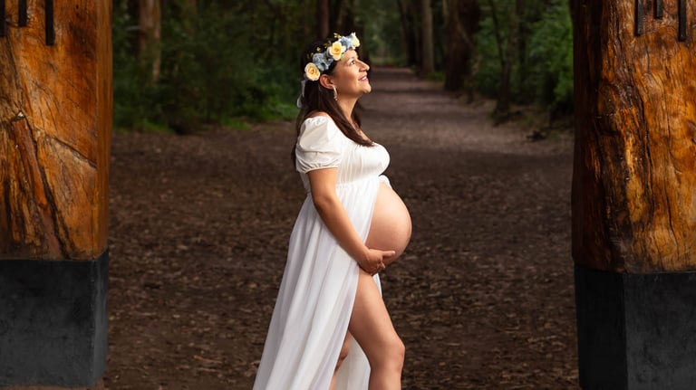 Fotografía profesional de maternidad embarazada con vestido blanco en un bosque encantado