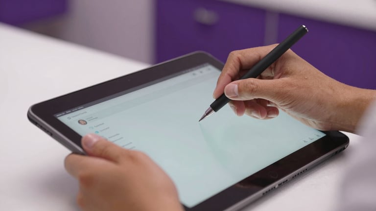 Close-up of a professional's hands in a Latin American beauty center using a high-end interface on a tablet. The setting is clean and premium with purple accents.