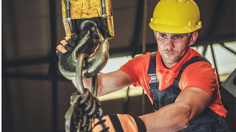 Técnico manuseando um moitão de um guindaste