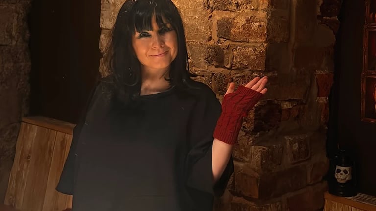 woman at Traitors event wearing a wig and red fingerless gloves.