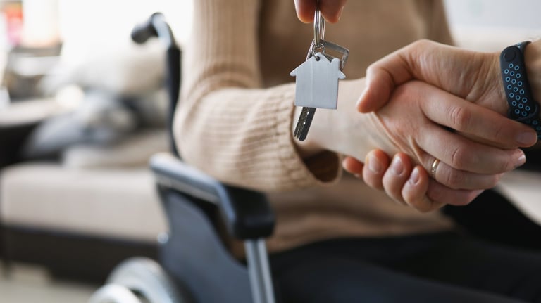 A participant in a wheelchair holding being assisted for better independence