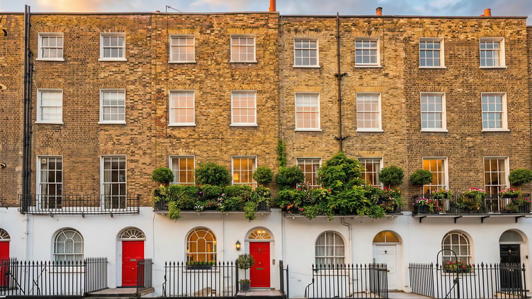 Traditional London brick terrace townhouses with red doors and window flower boxes.