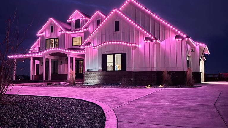 Modern white farmhouse decorated with vibrant pink exterior LED holiday trim lighting at night.