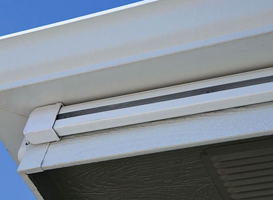 Close-up of a white seamless aluminum gutter system installed on a residential roofline.