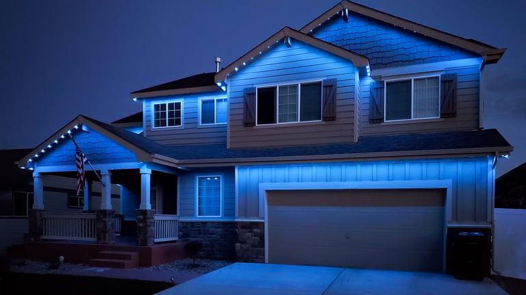 Modern two-story home with blue exterior LED trim lighting installed on the roofline and gables.
