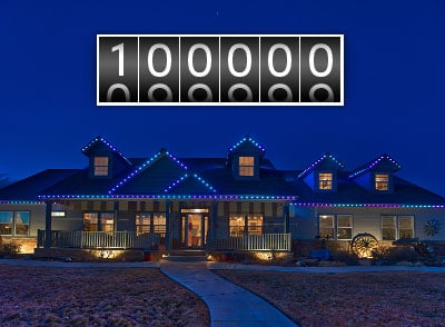 House decorated with 100,000 outdoor LED Christmas lights at night with a digital milestone counter.