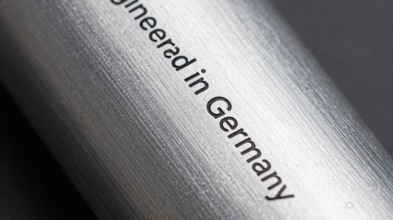 Close-up of a brushed aluminum housing of a cosmetic machine with the inscription 'Engineered in Germany', minimalist and sharp focus.