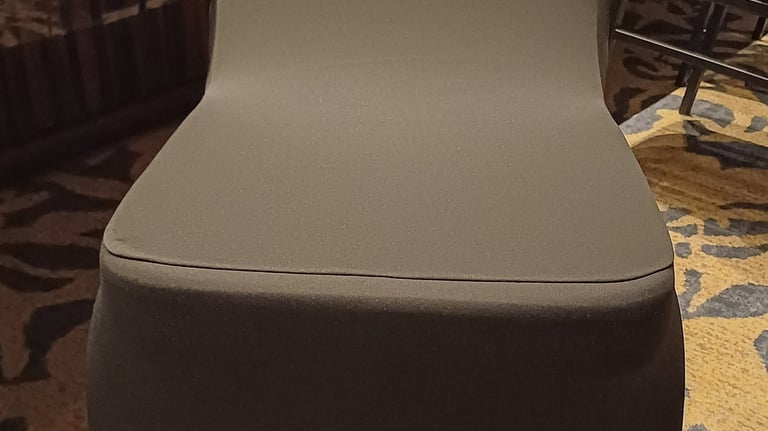 A sleek charcoal gray spandex chair cover for banquet and wedding event seating.