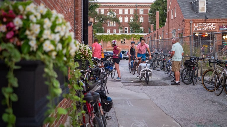 People on and near a large group of bikes downtown in an alley