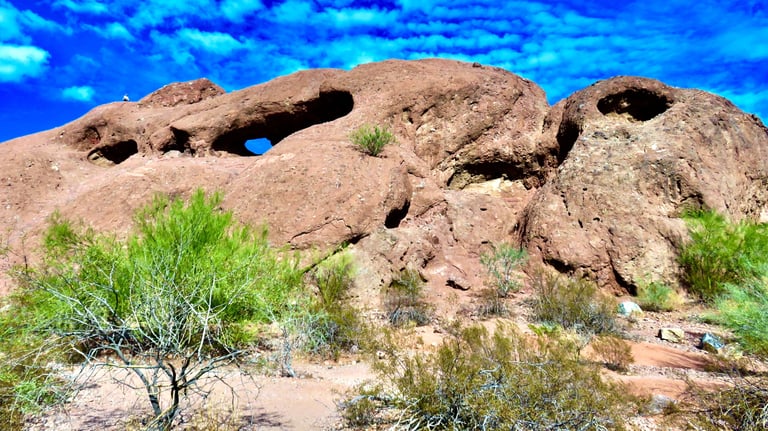 a rock formation in the desert with a blue sky and clouds