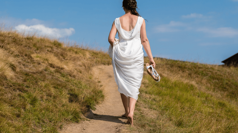 a woman in a white dress walking down a path