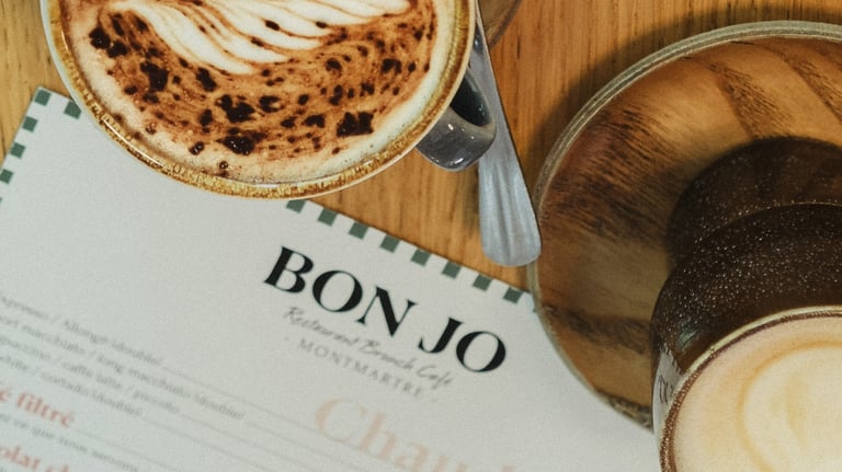 alt="Brunch coffee at Bon Jo café in Montmartre, Paris – artisan latte with menu featuring homemade drinks and breakfast spec