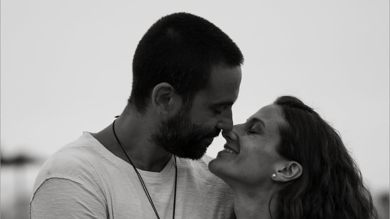 Black and white portrait of a happy couple smiling and touching noses during a romantic moment.