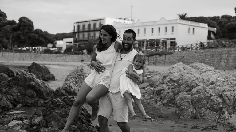 A happy family laughing on a rocky beach, creating memories during a coastal summer vacation.