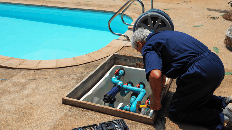 A pool tech is inspecting a pool's plumbing and pump system