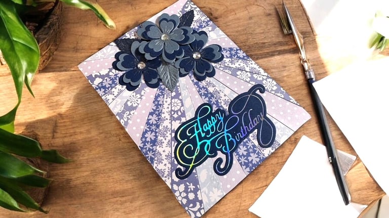 Handmade birthday card with 3D flowers on the front laying on a desk