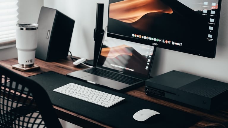 a desk with a computer monitor and a laptop