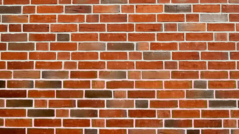 Nahaufnahme einer gleichmäßigen Wand aus roten und braunen Klinkersteinen 