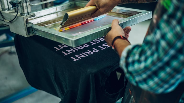 Una plancha de serigrafía con pintura de colores variados que van a ser plasmados en una camiseta.