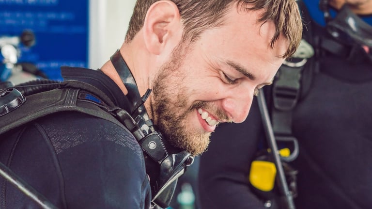 a man in a scuba suit is smiling and holding a cell phone