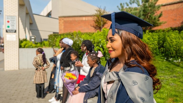 a black woman in a graduation cap and gown with her family taking lifestyle photography photos