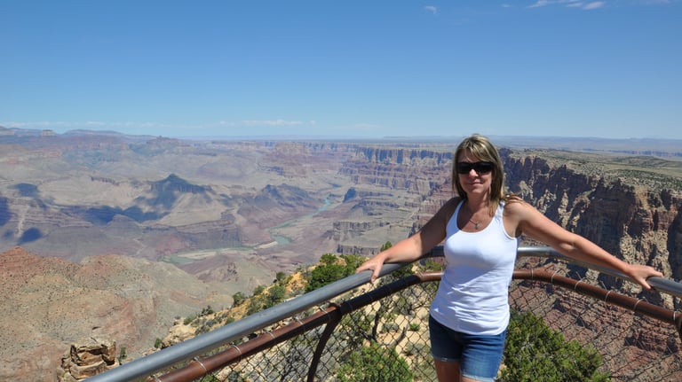 a woman standing on a railing overlooking the grand canyon