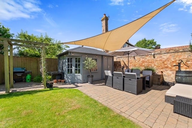 A block paved patio and outside seating area with pergola and log cabin