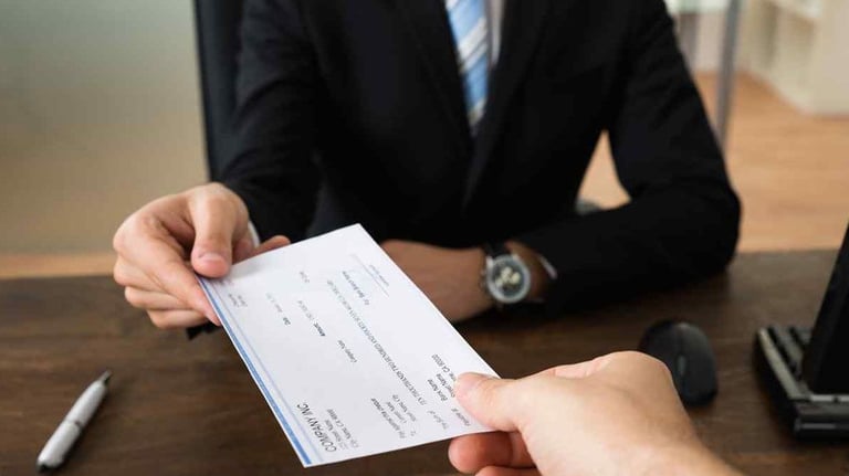 Abogado entregando cheque por pago de salarios y beneficios laborales pendientes