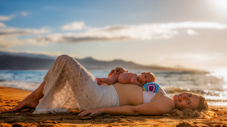 a pregnant woman laying on a beach