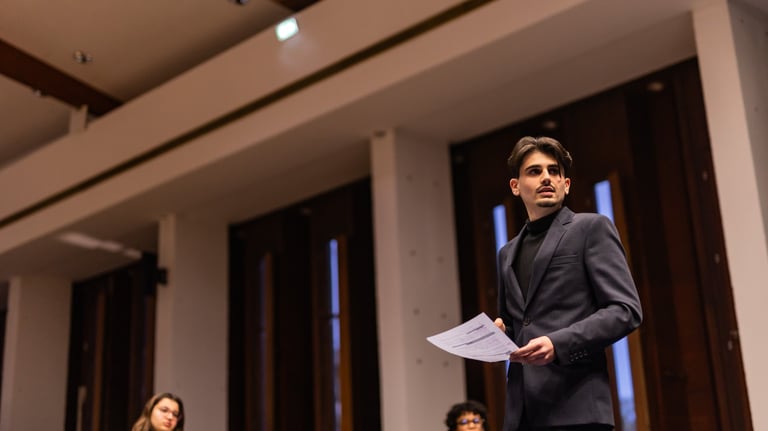 a man in a suit and tie is standing in front of a group of people