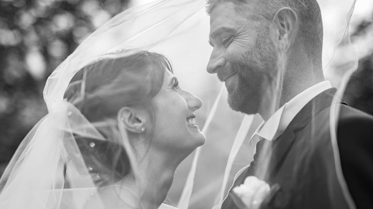 a bride and groom standing in front of a tree