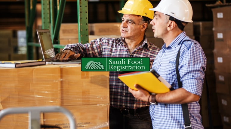 warehouse workers reviewing shipment documents on a laptop, representing customs clearance with Saudi Food Registration.