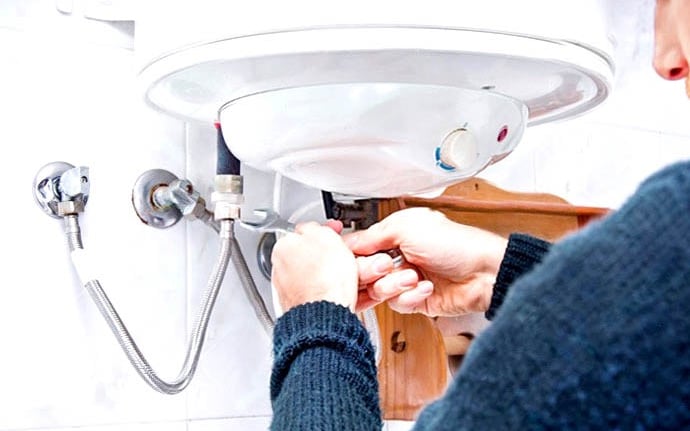 a woman in a blue sweater is fixing a sink