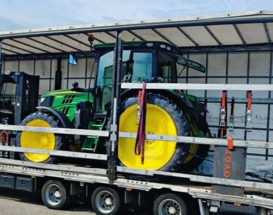 grüner Traktor mit gelben Rädern auf LKW