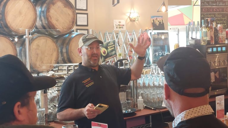 Seth Gross talking in front of an arrangement of barrels and glassware