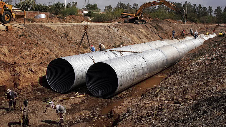 a group of people standing around a large pipe