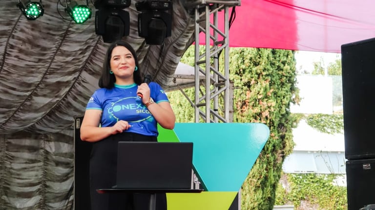 Raabe segurando microfone em palco de evento.