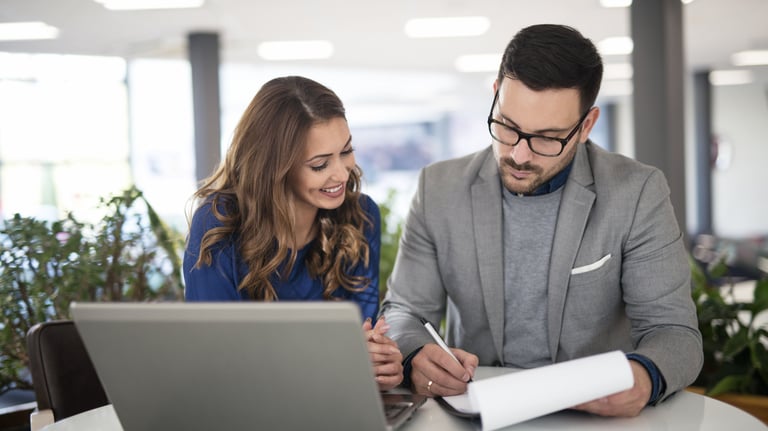 Profesionales revisando documentación y trabajando juntos frente a un ordenador en un entorno de ofi