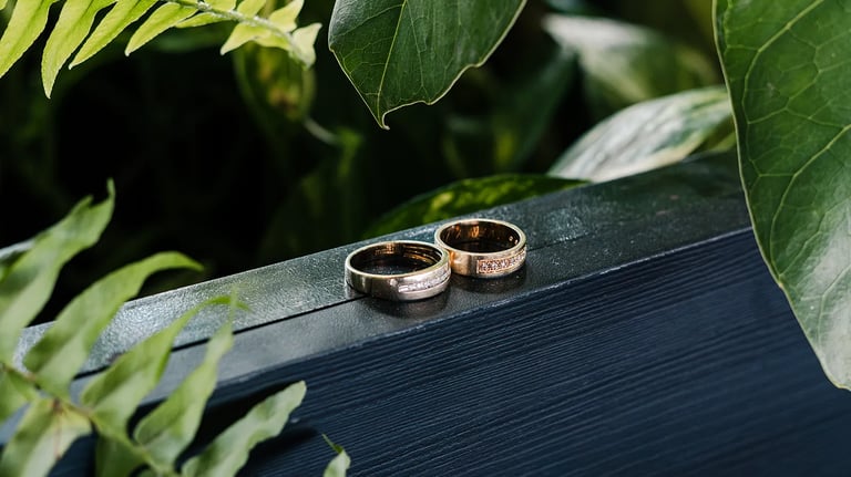 Fotografía premium de detalle de anillos de bodas reodeados de plantas en un fondo de madera azul en Quito