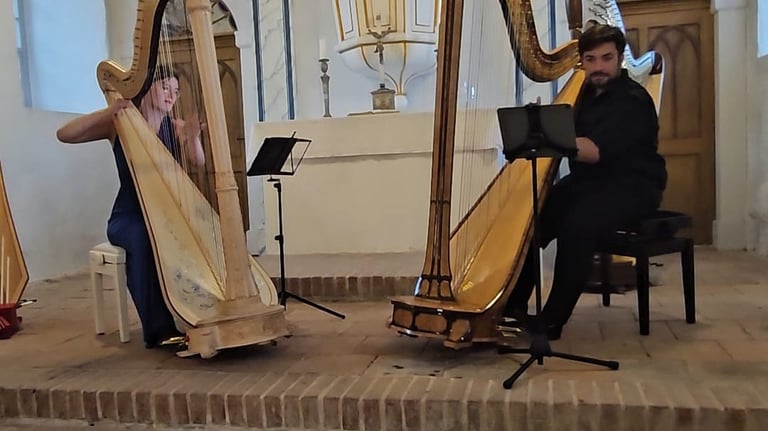 Maxi Treller und Clara Busemann sitzen jeweils an einer Harfe und spielen zusammen. Sie sind in einer Kirche